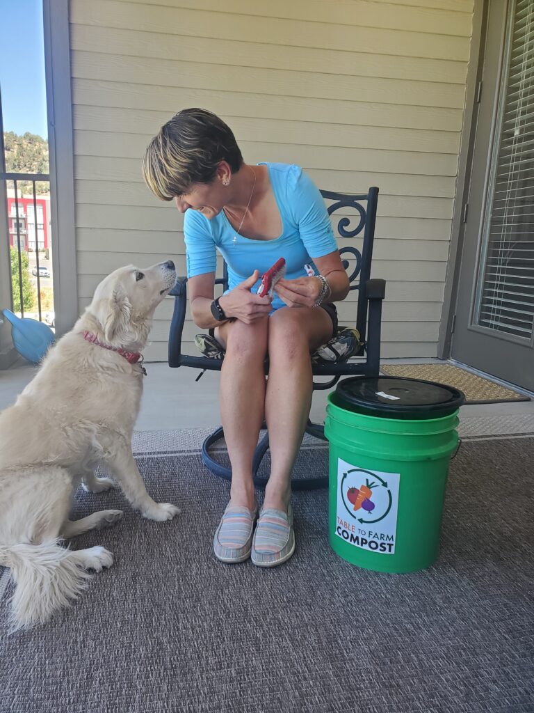 Zuzana Birova seated with her dog and a compost bucket.